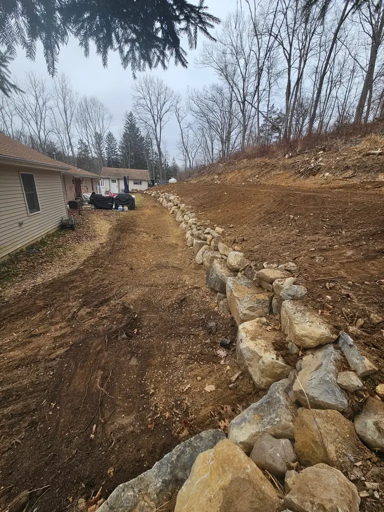 After: regraded slope with a new stone-lined edge for drainage and erosion control in Sussex County NJ